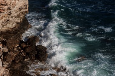 Okyanus dalgası arka planı deniz suyunu kırıyor kayalık kıyı dalgalı deniz turkuaz su gradyan köpüğü. Açık denizde büyük dalgalar. Yaz musonu. Bir deniz dalgasının beyaz tepesi.