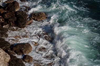 Okyanus dalgası arka planı deniz suyunu kırıyor kayalık kıyı dalgalı deniz turkuaz su gradyan köpüğü. Açık denizde büyük dalgalar. Yaz musonu. Bir deniz dalgasının beyaz tepesi.