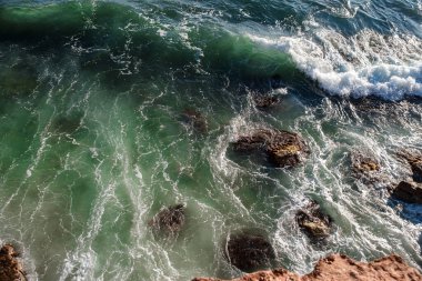 Okyanus dalgası arka planı deniz suyunu kırıyor kayalık kıyı dalgalı deniz turkuaz su gradyan köpüğü. Açık denizde büyük dalgalar. Yaz musonu. Bir deniz dalgasının beyaz tepesi.
