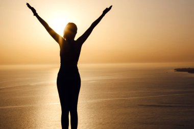 Kendine güveni tam bir kadın gün doğumunda deniz kenarında kollarını açar. sağlıklı yaşam tarzı geçmişi
