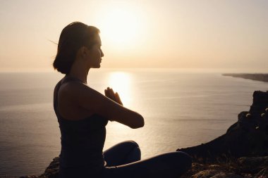 Gün batımı denizinde yoga yapan genç bir kadın. Nilüfer pozisyonunda meditasyon. Yoga silueti. Uyum ve meditasyon konsepti. Sağlıklı yaşam tarzı