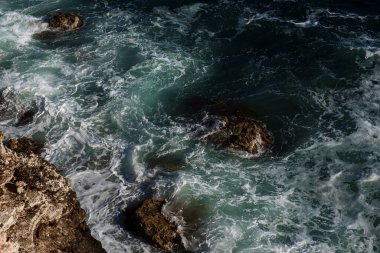 Okyanus dalgası arka planı deniz suyunu kırıyor kayalık kıyı dalgalı deniz turkuaz su gradyan köpüğü. Açık denizde büyük dalgalar. Yaz musonu. Bir deniz dalgasının beyaz tepesi.