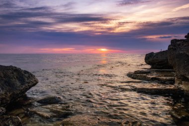 Dramatik gün batımı. Dalga yıpranmış kayaların ve kayaların üzerinden akıyor. Öndeki doğal bir gölet. Hdr işlendi.