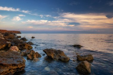 Dramatik gün batımı. Dalga yıpranmış kayaların ve kayaların üzerinden akıyor. Öndeki doğal bir gölet. Hdr işlendi.
