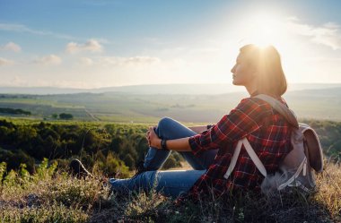 Genç hippi kız bakış açısıyla gün batımının tadını çıkarıyor. Sırt çantalı gezgin kadın. Doğanın günbatımının tadını çıkarıyorum. Gün doğumunda dağlarda dinleniyorlar. Trek konsepti