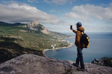 Adam akıllı telefonuyla dağların muhteşem manzarasının fotoğrafını çekiyor. seyahat ve keşif kavramı
