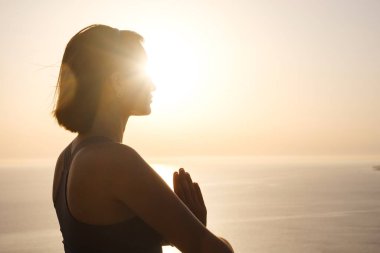 Gün batımı denizinde yoga yapan genç bir kadın. Nilüfer pozisyonunda meditasyon. Yoga silueti. Uyum ve meditasyon konsepti. Sağlıklı yaşam tarzı