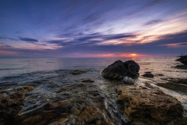 Dramatik gün batımı. Dalga yıpranmış kayaların ve kayaların üzerinden akıyor. Öndeki doğal bir gölet. Hdr işlendi.