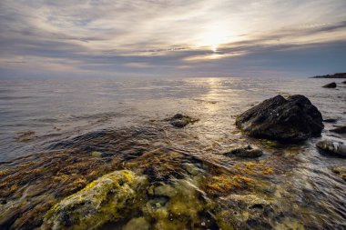 Dramatik gün batımı. Dalga yıpranmış kayaların ve kayaların üzerinden akıyor. Öndeki doğal bir gölet. Hdr işlendi.