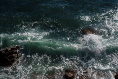 Okyanus dalgası arka planı deniz suyunu kırıyor kayalık kıyı dalgalı deniz turkuaz su gradyan köpüğü. Açık denizde büyük dalgalar. Yaz musonu. Bir deniz dalgasının beyaz tepesi.