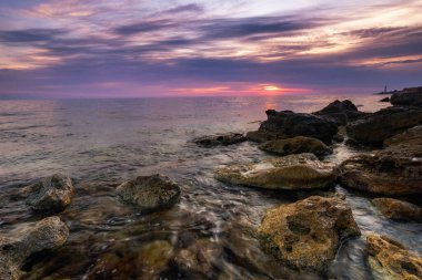 Dramatik gün batımı. Dalga yıpranmış kayaların ve kayaların üzerinden akıyor. Öndeki doğal bir gölet. Hdr işlendi.