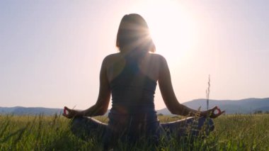 Genç bir Asyalı kadın gün batımında tarlada meditasyon yapıyor. Egzersiz yapan kadın doğa arka planında fitness yaşam kulübü için hayati önem taşıyor ve meditasyon yapıyor. Sağlıklı ve Yoga Konsepti