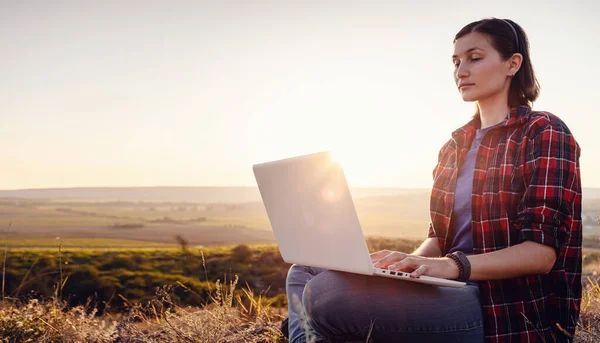 Girl working on her computer on the top of the mountain. Relaxing and working in mountains at sunrise.