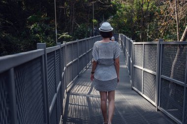 Elbiseli ve şapkalı bir kadın, Chiang Mai, Tayland 'daki Kraliçe Sirikit Botanik Bahçeleri' nde orman ortasında tek başına duruyor.