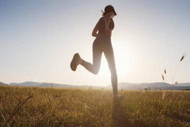 Gün batımında koşan bir kadın. Kadın fitness silueti, gün doğumu, koşu, sağlık konsepti..