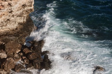 Okyanus dalgası arka planı deniz suyunu kırıyor kayalık kıyı dalgalı deniz turkuaz su gradyan köpüğü. Açık denizde büyük dalgalar. Yaz musonu. Bir deniz dalgasının beyaz tepesi.