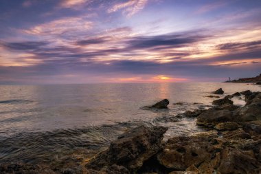 Dramatik gün batımı. Dalga yıpranmış kayaların ve kayaların üzerinden akıyor. Öndeki doğal bir gölet. Hdr işlendi.