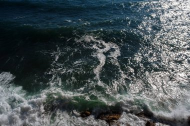 Okyanus dalgası arka planı deniz suyunu kırıyor kayalık kıyı dalgalı deniz turkuaz su gradyan köpüğü. Açık denizde büyük dalgalar. Yaz musonu. Bir deniz dalgasının beyaz tepesi.