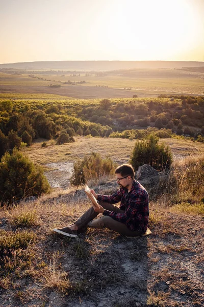 man travel relax in the holiday. seats relax read books on rocky cliffs. Silhouette of man reading book at sky sunset . warm tone and soft focus