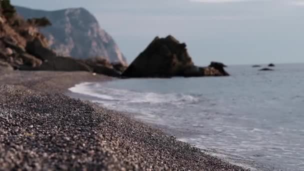 Golven Komen Gaan Een Verlaten Rotsachtig Strand Met Bergen Achtergrond — Stockvideo