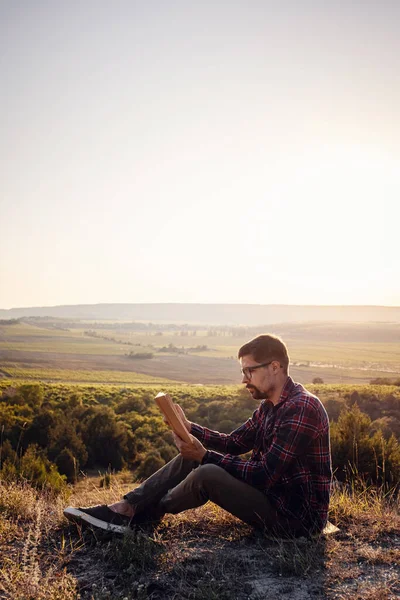 man travel relax in the holiday. seats relax read books on rocky cliffs. Silhouette of man reading book at sky sunset . warm tone and soft focus