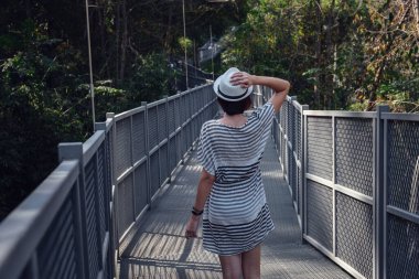 Elbiseli ve şapkalı bir kadın, Chiang Mai, Tayland 'daki Kraliçe Sirikit Botanik Bahçeleri' nde orman ortasında tek başına duruyor.