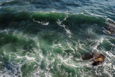 Okyanus dalgası arka planı deniz suyunu kırıyor kayalık kıyı dalgalı deniz turkuaz su gradyan köpüğü. Açık denizde büyük dalgalar. Yaz musonu. Bir deniz dalgasının beyaz tepesi.