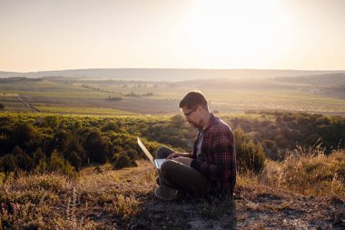 Dağın kenarında dizüstü bilgisayarı olan bir adam vadiyi büyüleyici bir şekilde görüyor. Hücresel ağ broşürü kapsama alanı. 5G.