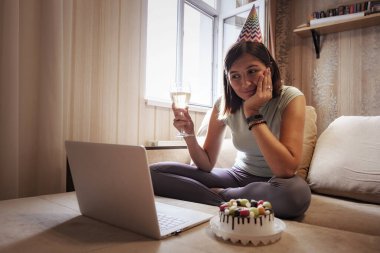 Karantina zamanında doğum gününü kutlayan bir kız. Doğum gününü arkadaşlarıyla sanal parti aracılığıyla kutlayan bir kadın. Otantik dekore edilmiş ev işyeri. Coronavirüs salgını 2020.