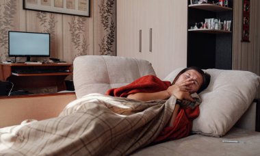 Hasta ve Grip Kadın. Soğuk algınlığına yakalandım. Kadın kendini üşümüş hissediyor. Evdeki kanepede dinleniyor.