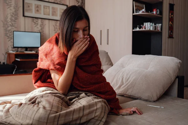 Sick and Flu Woman. Caught Cold. Woman feeling cold with blanket resting on the sofa at home