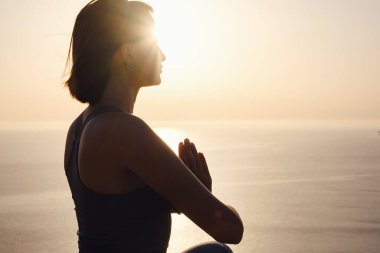 Gün batımı denizinde yoga yapan genç bir kadın. Nilüfer pozisyonunda meditasyon. Yoga silueti. Uyum ve meditasyon konsepti. Sağlıklı yaşam tarzı