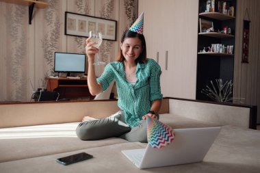 Sanal parti aracılığıyla karantinada doğum gününü kutlayan bir kız. Coronavirus salgını 2020. Bir kadeh şarap tutan kadın.