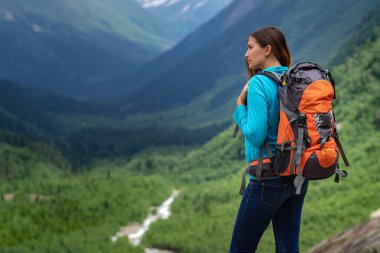 Dağın tepesinde, vadi manzarasının tadını çıkaran bir gezgin. Yolculuk konsepti, yazı için yer, atmosferik destansı an. Yürüyüş, yürüyüş ya da tırmanış için görüntü. Kuzey Kafkasya, Dombai, Rusya.