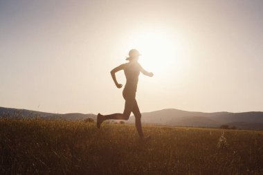 Gün batımında koşan bir kadın. Kadın fitness silueti, gün doğumu, koşu, sağlık konsepti..
