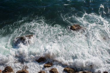 Okyanus dalgası arka planı deniz suyunu kırıyor kayalık kıyı dalgalı deniz turkuaz su gradyan köpüğü. Açık denizde büyük dalgalar. Yaz musonu. Bir deniz dalgasının beyaz tepesi.