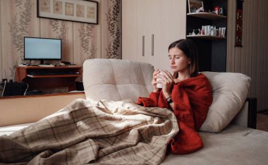 Hasta ve Grip Kadın. Soğuk algınlığına yakalandım. Kadın kendini üşümüş hissediyor. Evdeki kanepede dinleniyor.