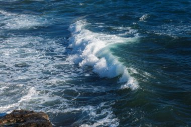 Okyanus dalgası arka planı deniz suyunu kırıyor kayalık kıyı dalgalı deniz turkuaz su gradyan köpüğü. Açık denizde büyük dalgalar. Yaz musonu. Bir deniz dalgasının beyaz tepesi.