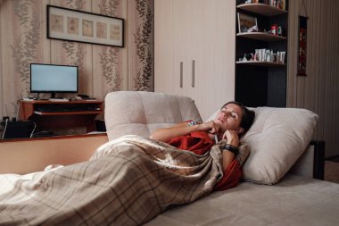 Hasta ve Grip Kadın. Soğuk algınlığına yakalandım. Kadın kendini üşümüş hissediyor. Evdeki kanepede dinleniyor.