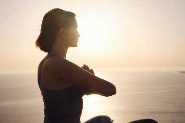 Gün batımı denizinde yoga yapan genç bir kadın. Nilüfer pozisyonunda meditasyon. Yoga silueti. Uyum ve meditasyon konsepti. Sağlıklı yaşam tarzı