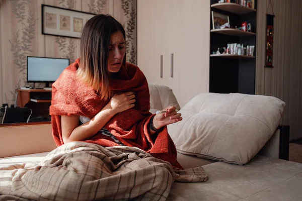 Sick and Flu Woman. Caught Cold. Woman feeling cold with blanket resting on the sofa at home