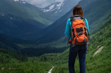 Dağın tepesinde, vadi manzarasının tadını çıkaran bir gezgin. Yolculuk konsepti, yazı için yer, atmosferik destansı an. Yürüyüş, yürüyüş ya da tırmanış için görüntü. Kuzey Kafkasya, Dombai, Rusya.