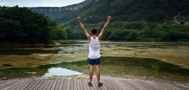 Genç erkek hippi gölün güzel manzarasına bakıyor. Güzel bir özgürlük anı ve doğada huzurlu bir atmosfer. Arka plan.