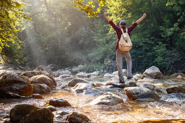 快乐的男性徒步旅行者在河边的森林里举手 发现和旅行的理念和概念 — 图库照片
