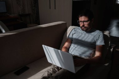 Uzaktan kumanda. Dizüstü bilgisayarda çalışan bir adam evdeki koltukta oturuyor. Metin için Boşluğu Kopyala. Serbest çalışan hipster, ortaklarıyla çalışır, çalışır ya da iletişim kurar.