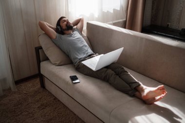 Evde kulaklıklı ve defterli bir adam var. Genç hipster internetten kulaklık takıyor. Dizüstü bilgisayarda Webinar Podcast izliyor. Eğitim kursu ya da müzik dinliyor.