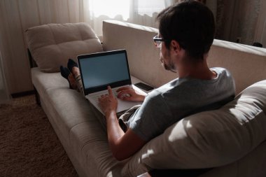 Uzaktan kumanda. Dizüstü bilgisayarda çalışan bir adam evdeki koltukta oturuyor. Metin için Boşluğu Kopyala. Serbest çalışan hipster, ortaklarıyla çalışır, çalışır ya da iletişim kurar.