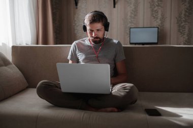Evde kulaklıklı ve defterli bir adam var. Genç hipster internetten kulaklık takıyor. Dizüstü bilgisayarda Webinar Podcast izliyor. Eğitim kursu ya da müzik dinliyor.