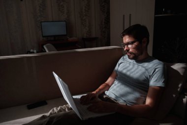 Uzaktan kumanda. Dizüstü bilgisayarda çalışan bir adam evdeki koltukta oturuyor. Metin için Boşluğu Kopyala. Serbest çalışan hipster, ortaklarıyla çalışır, çalışır ya da iletişim kurar.