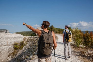 Sırt çantalı iki yürüyüşçü ve diğer tırmanma ekipmanları Rock 'ın tepesinde kalıyor. Adam eliyle güzergahı işaret ediyor. Plan, vizyon ve görev konsepti.